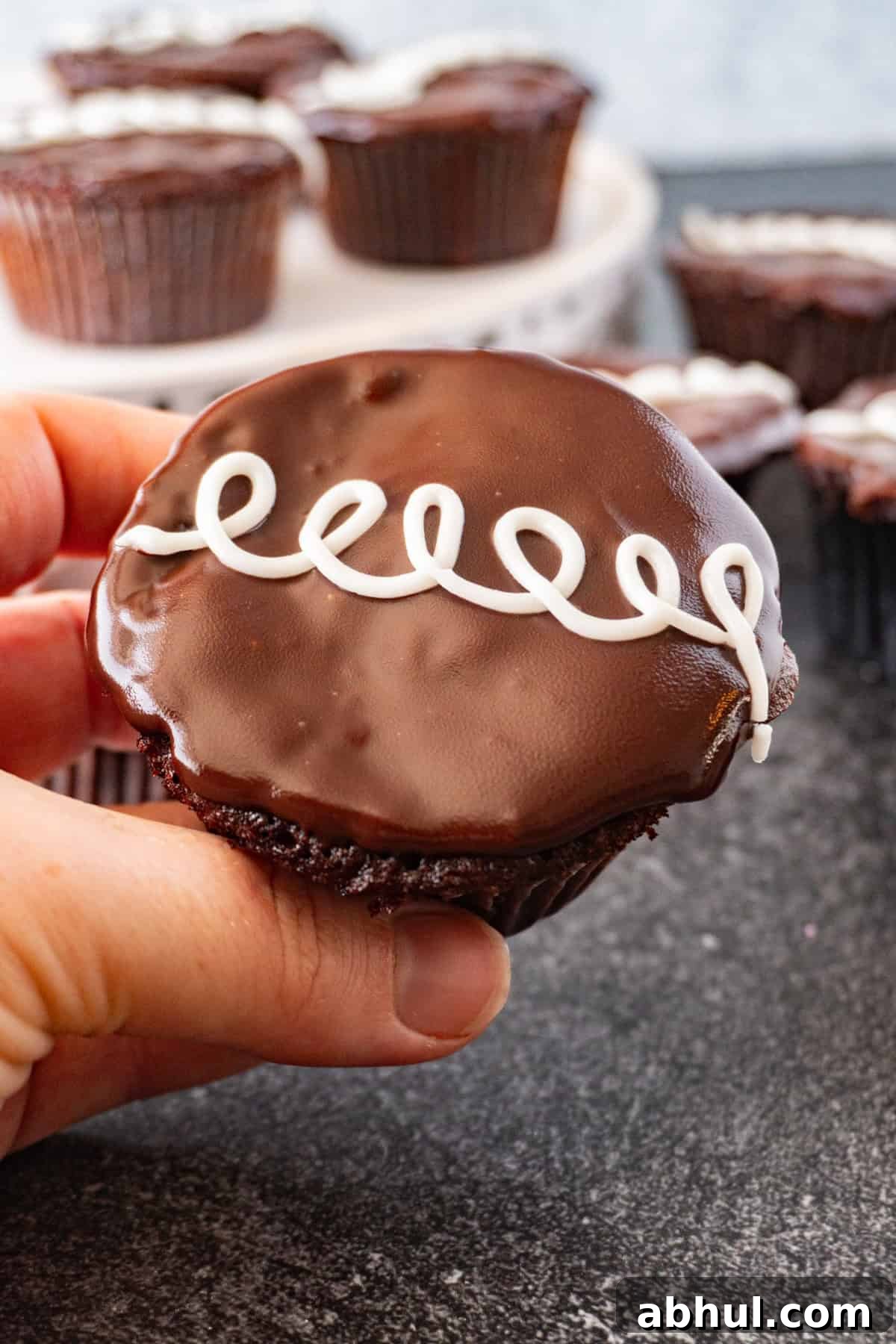 holding a cream filled cupcake.