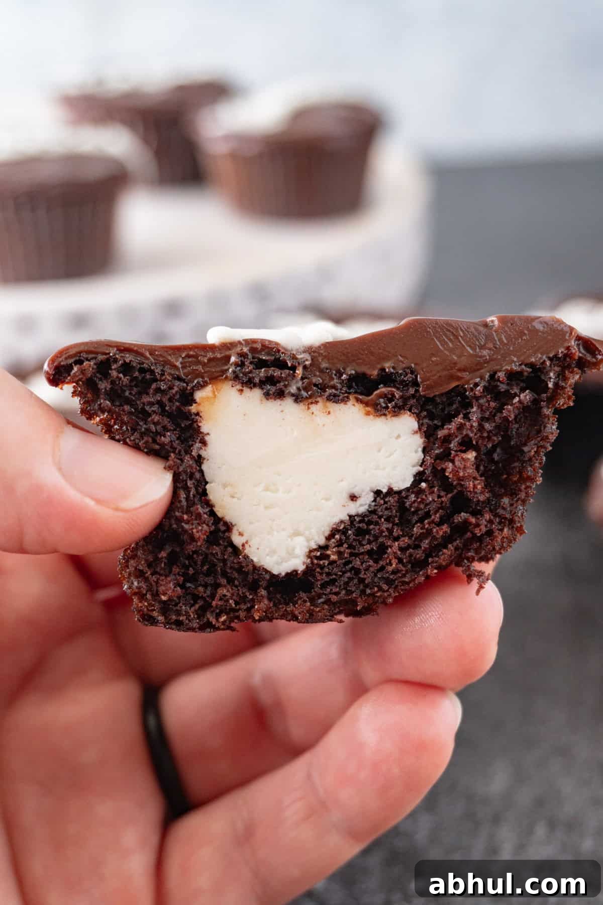 holding a cupcake cut in half to show the filled center.