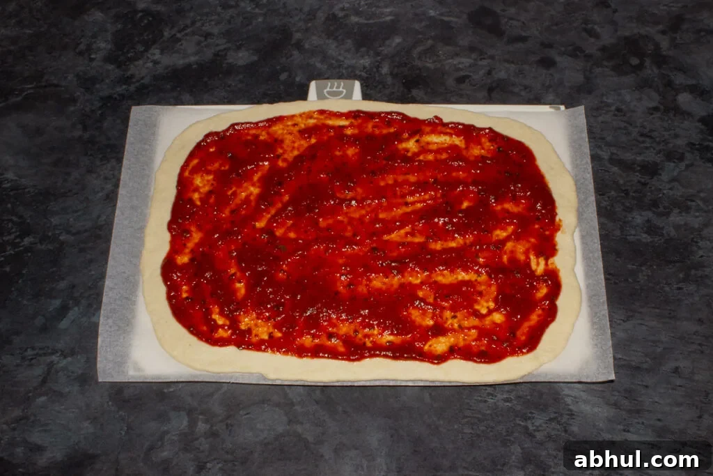 Pizza dough with tomato sauce spread over it