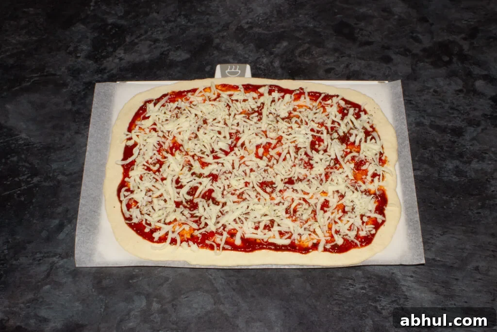An unbaked pizza on baking paper, ready for the oven