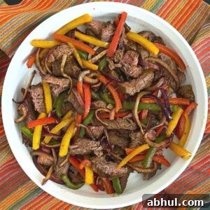 Air fryer steak fajitas with bell peppers and onion in a serving dish.
