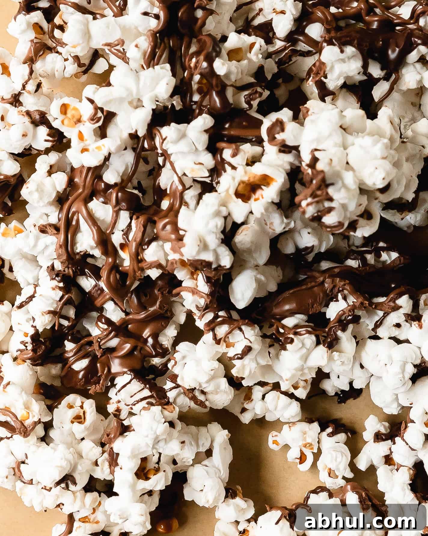 Chocolate covered popcorn is a quick, easy, salty sweet snack made with made using freshly popped popcorn topped with rich, melted chocolate drizzles. For even more flavor, top this chocolate popcorn with your favorite toppings like nuts or candy. Skip the store bought version and learn how to make these chocolate drizzled popcorn in a few easy steps.