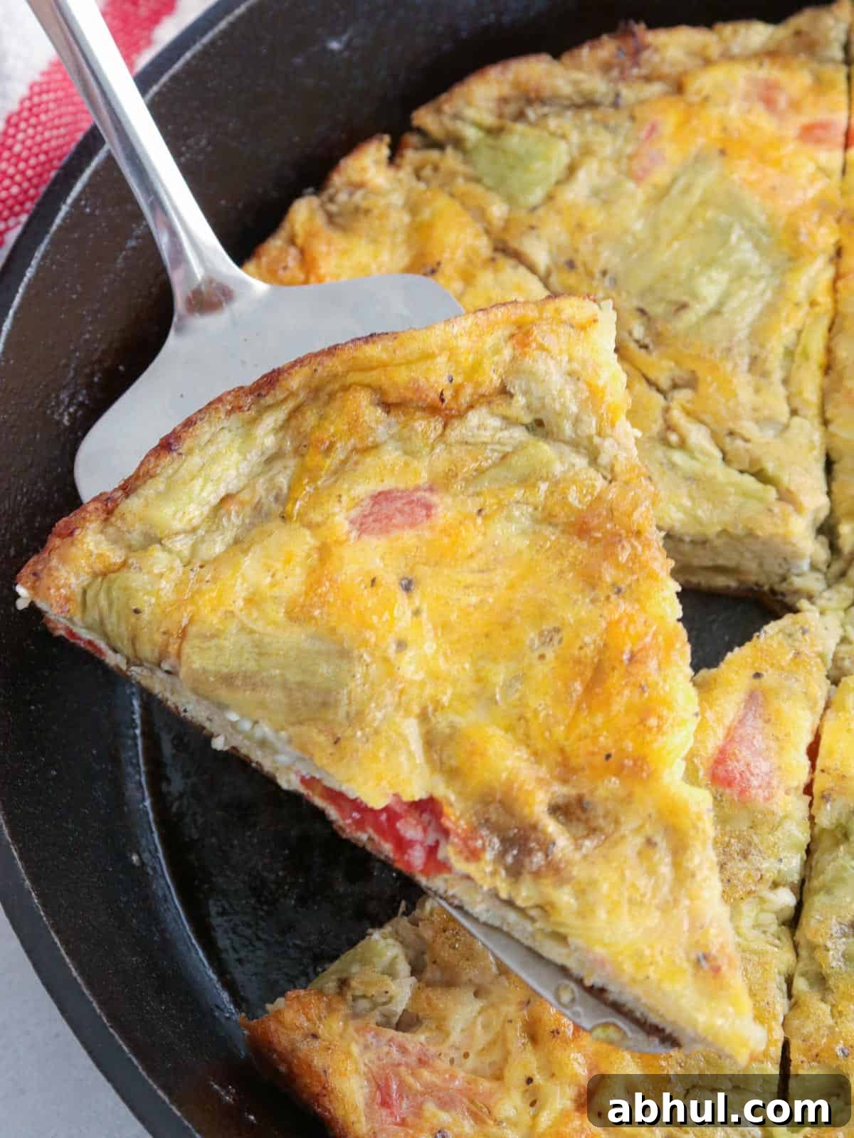 serving a slice of eggplant and tomato frittata from a cast iron skillet.