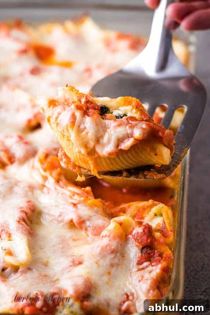 One cheesy pasta shell being lifted from the baking dish.