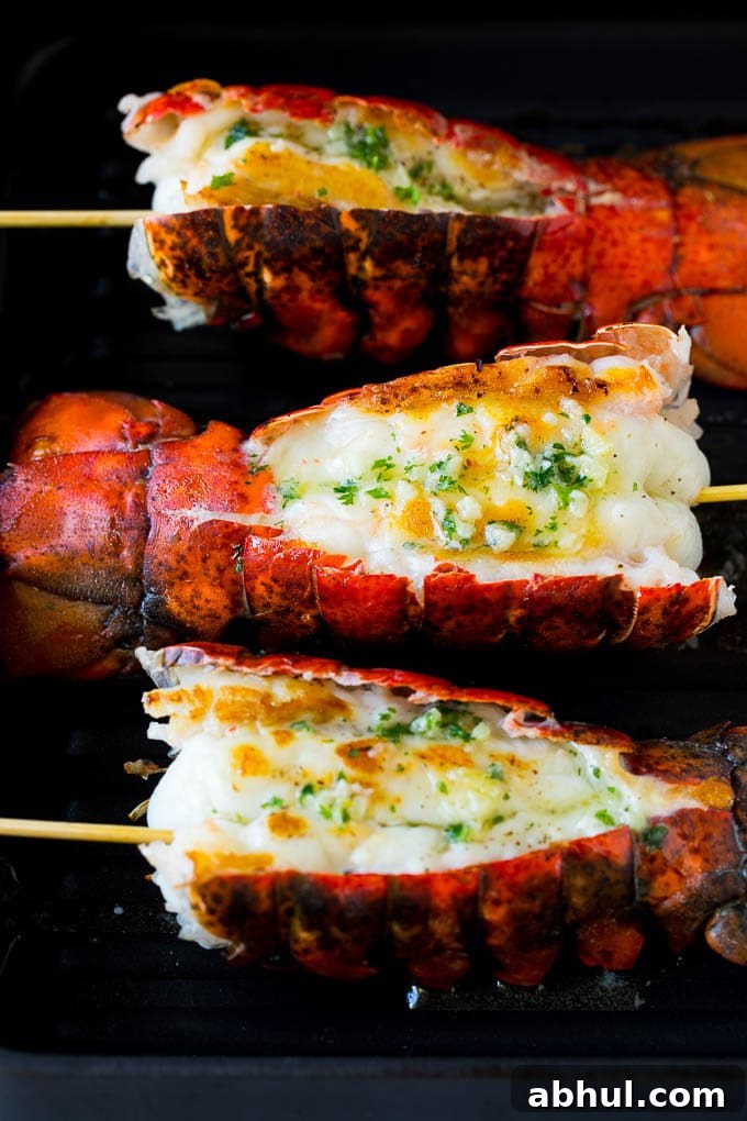 Cooked lobster tails on a grill pan, brushed with butter.