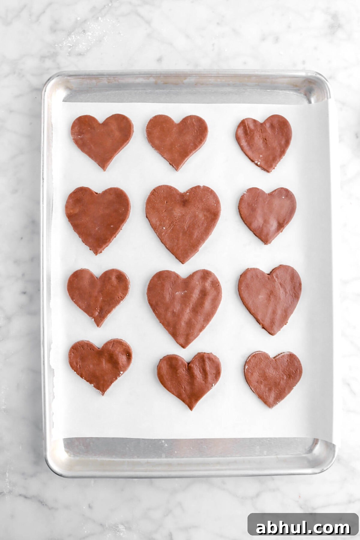 Chocolate-Strawberry Linzer Cookie Recipe for Perfect Sandwich Cookies 21 heart shaped chocolate cookie dough on lined baking sheet
