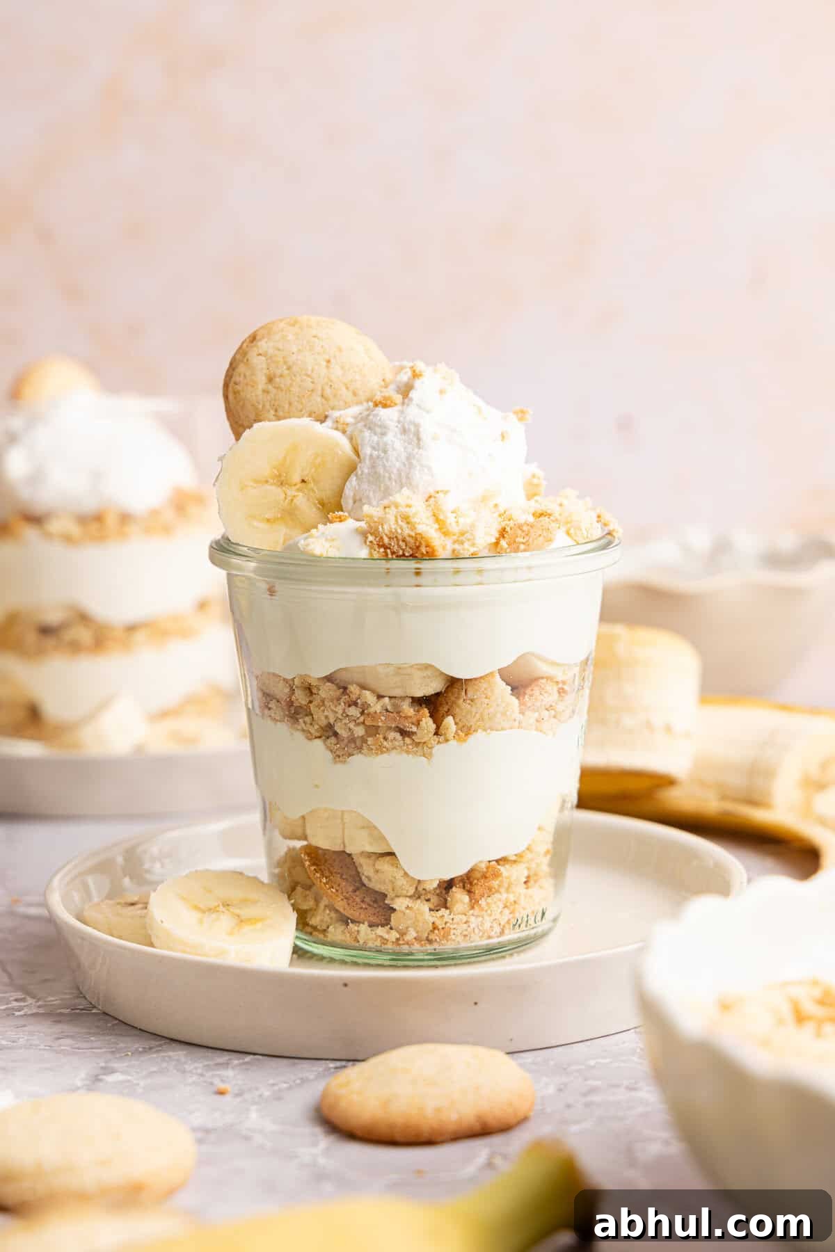 a banana pudding cup with a vanilla wafer and whipped cream on top