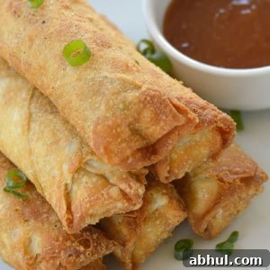 Crispy Air-Fried Egg Rolls: Quick Recipe for Homemade Crunch 8 six crispy egg rolls stacked beside a tasty sauce