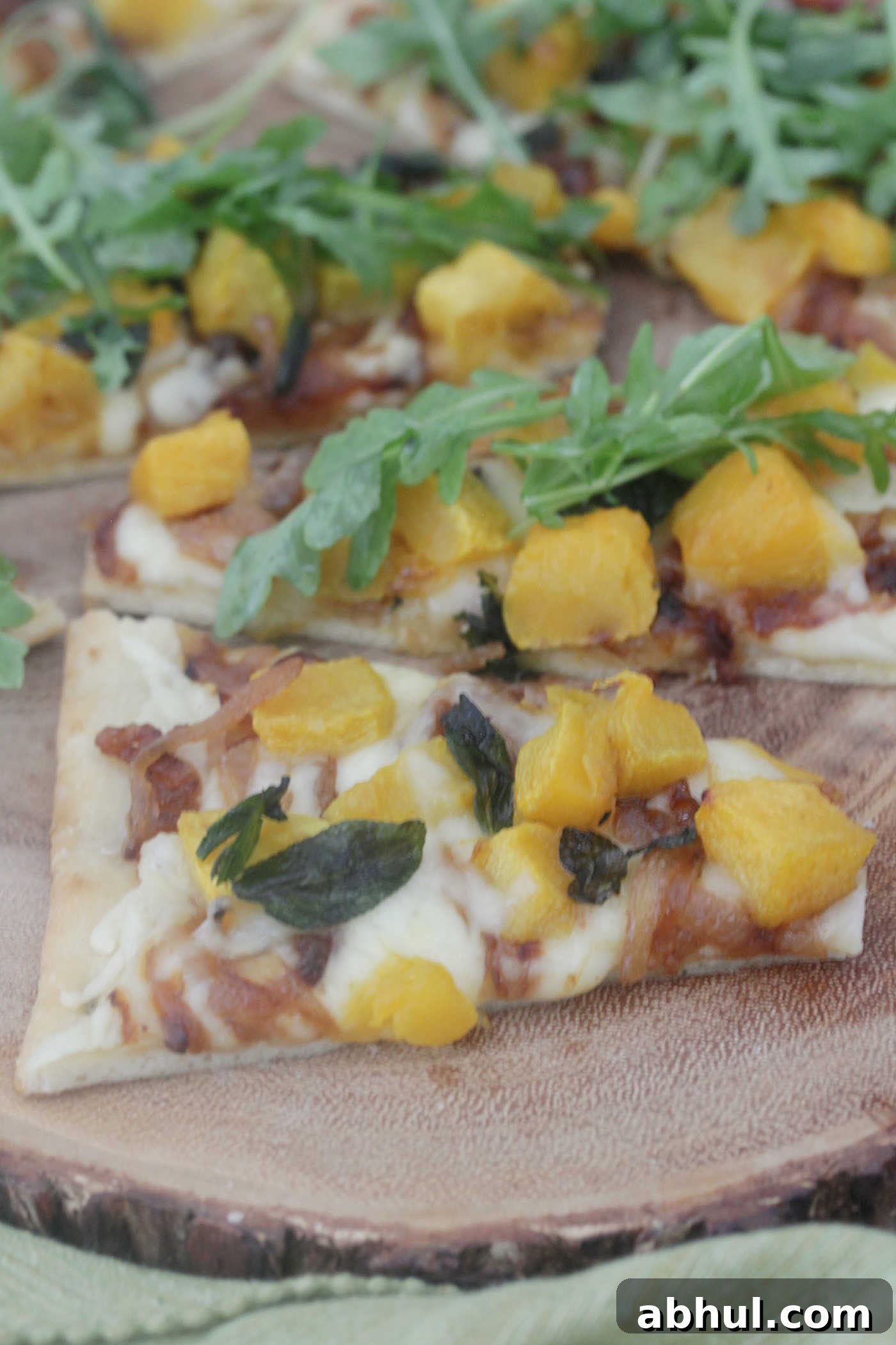 Butternut squash and onion flatbread pizza on a wooden cutting board