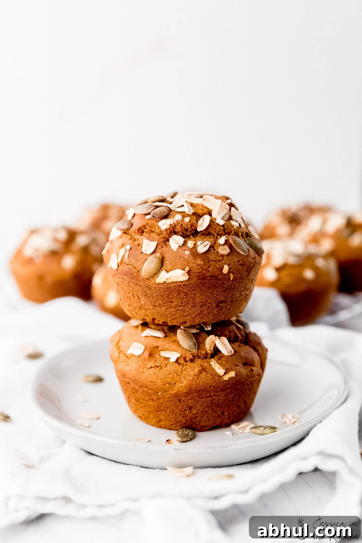 Side shot of two stacked vegan pumpkin muffins on a plate.