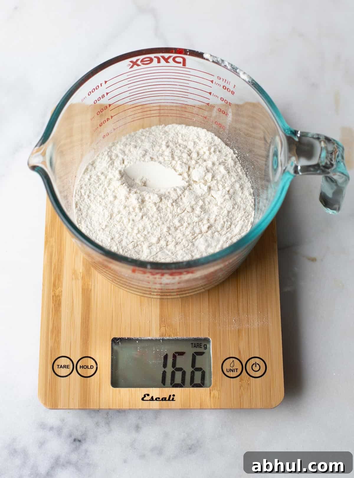A digital scale measuring flour in a glass dish