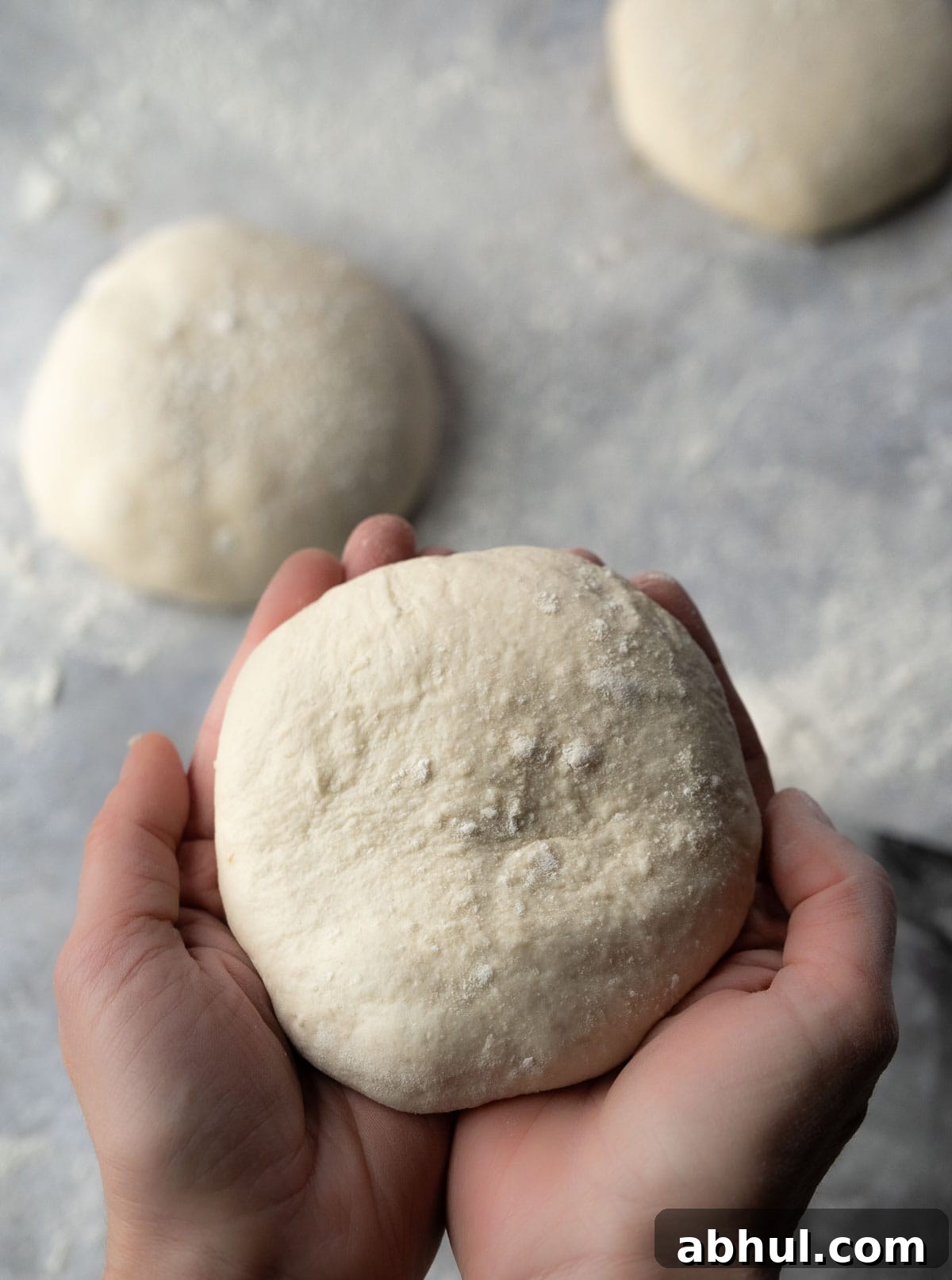 hands cupped to hold a sourdough pizza dough