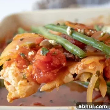 Mediterranean Baked Fish, close up on spatula with tomato mixture and green beans.