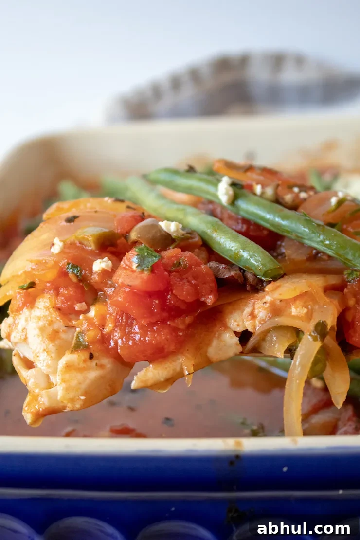Mediterranean Baked Fish, close up on spatula with tomato mixture and green beans.