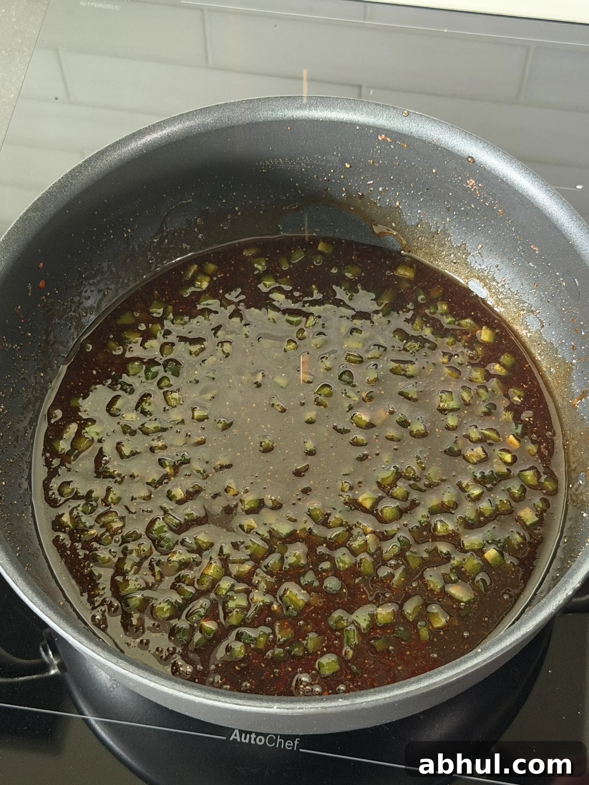 Jalapeños and aromatics sauteing in a pan for honey jalapeño sauce