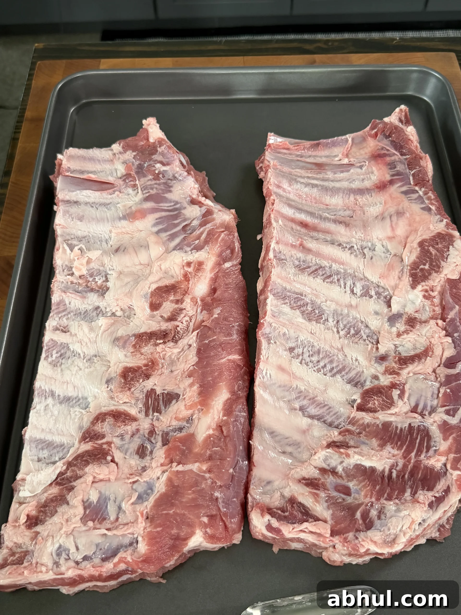 Raw pork ribs in a metal pan ready for smoking preparation