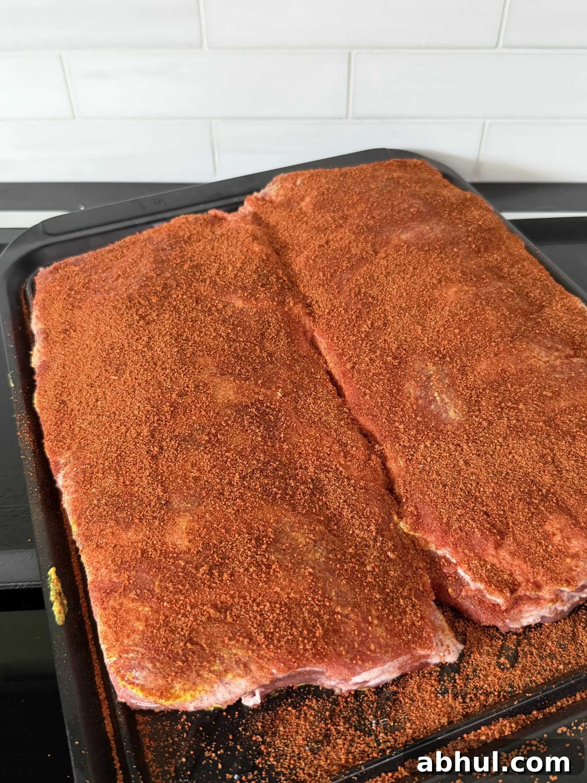 Seasoned pork ribs with dry rub in a baking pan ready for the smoker