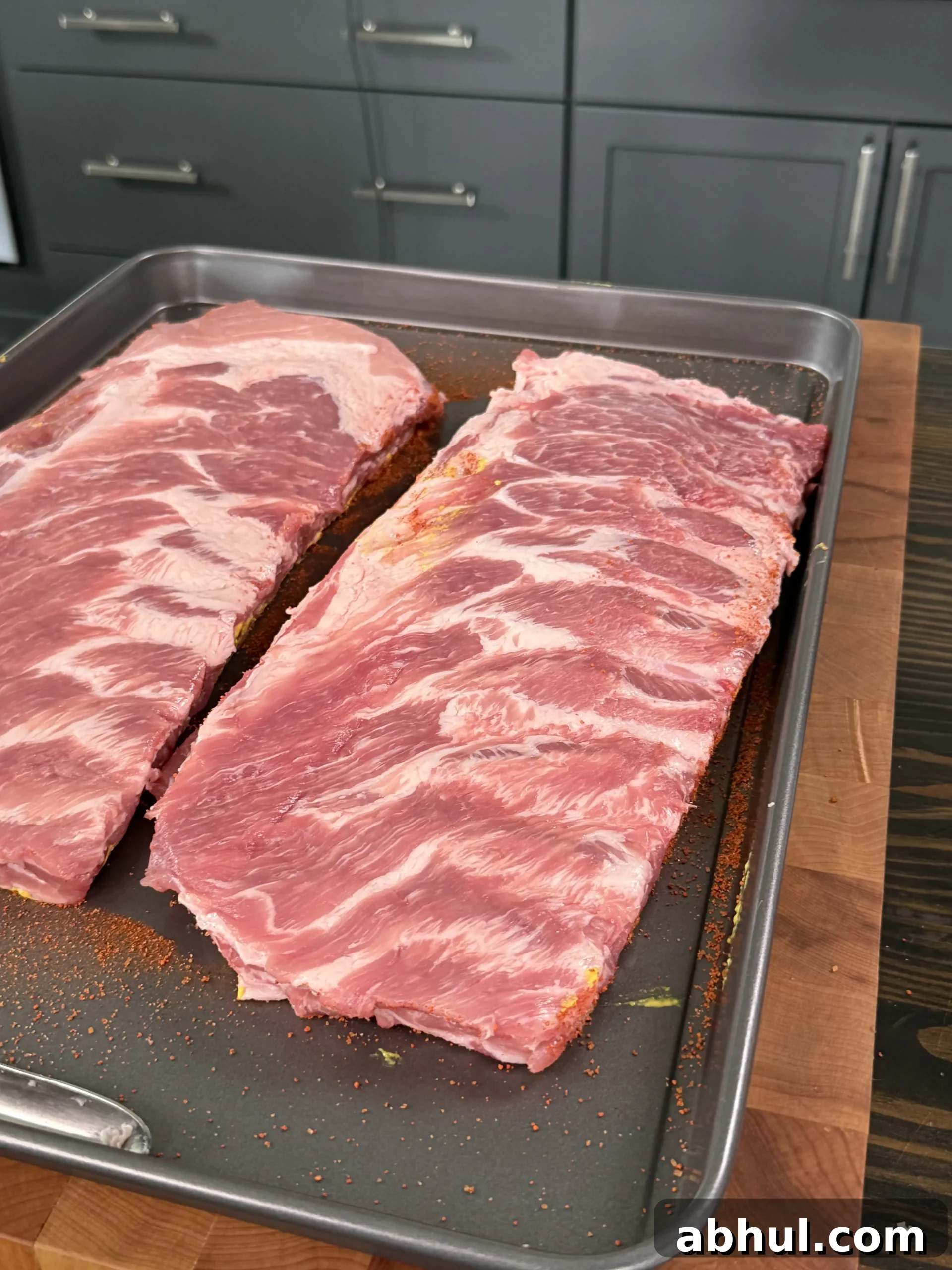 Raw pork ribs seasoned with rub on a baking sheet