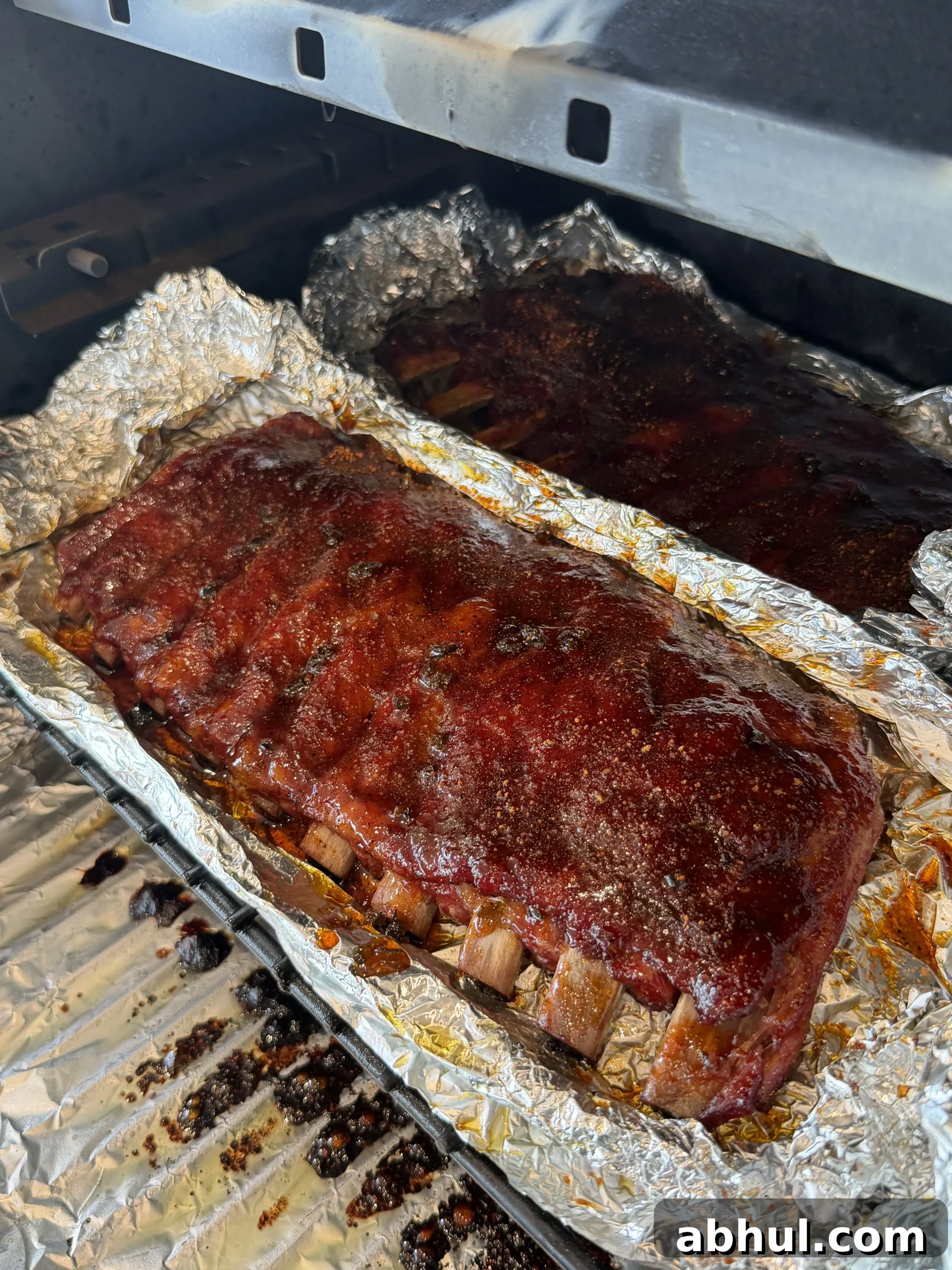 Pellet smoked ribs wrapped in foil on the grill during the wrap phase
