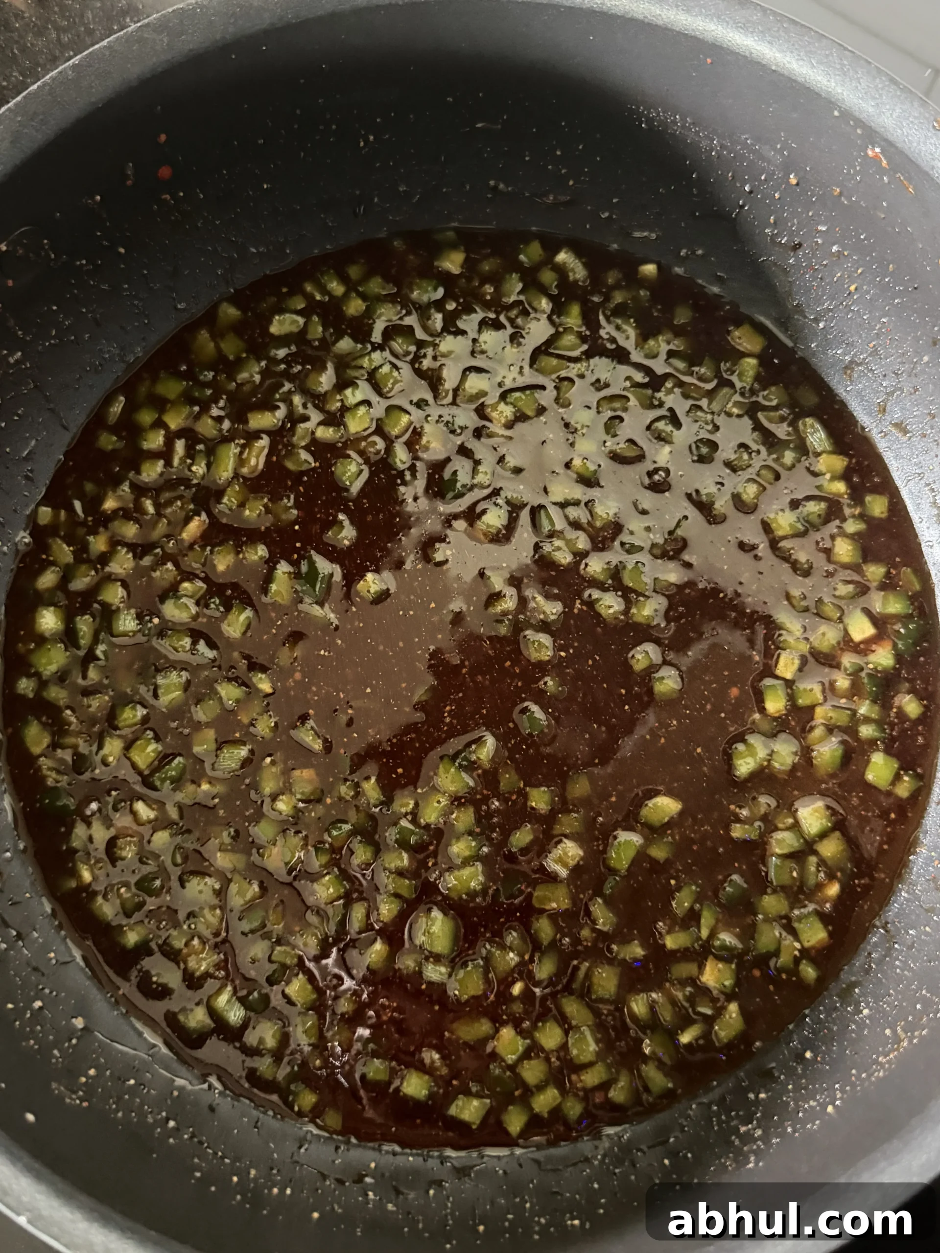 Honey jalapeño BBQ sauce with green onions simmering in a pan
