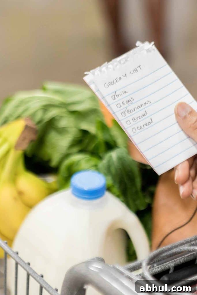 Small grocery list written on note pad, being held over a grocery cart with milk, greens and bananas.