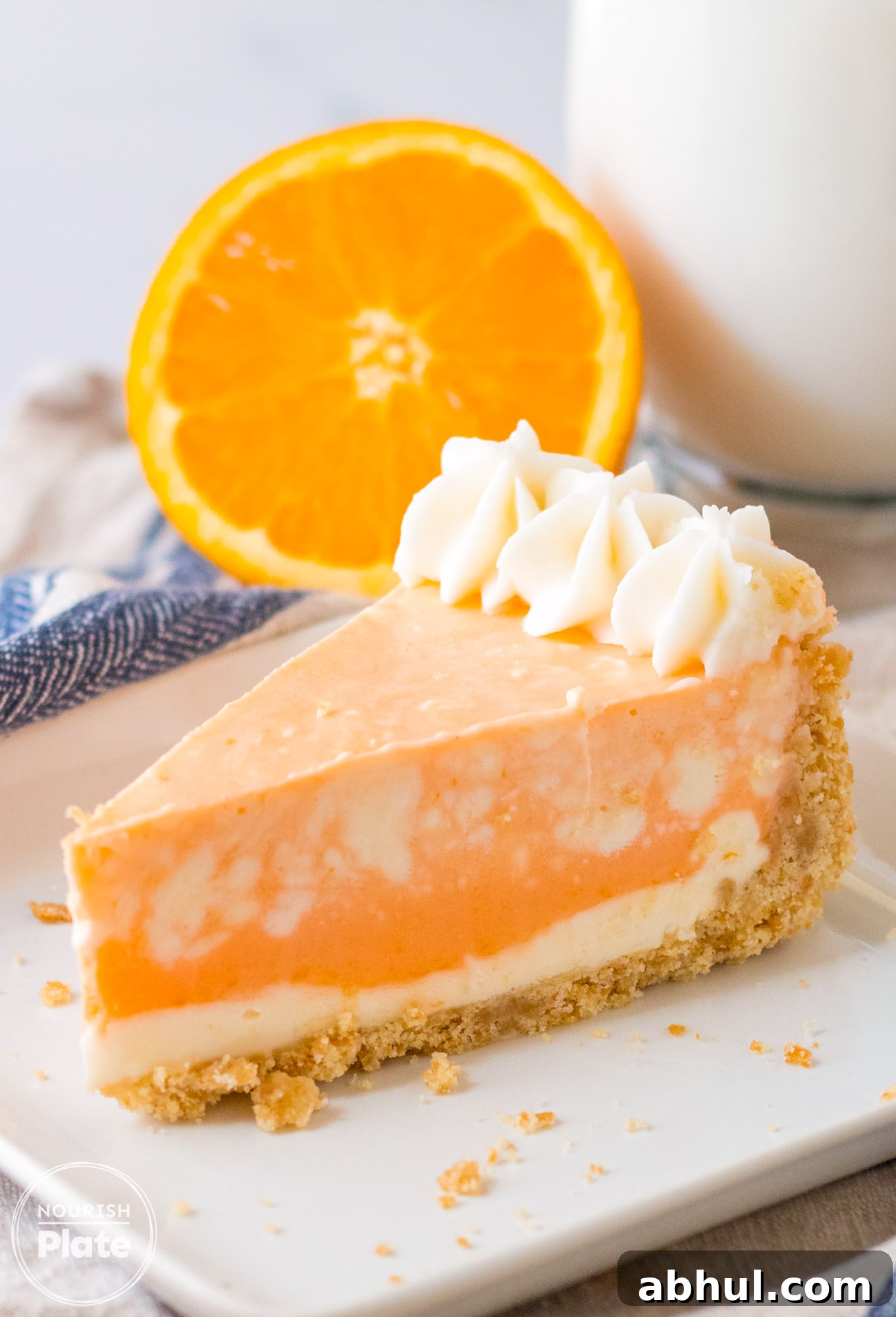 A slice of orange creamsicle cheesecake served on a white plate