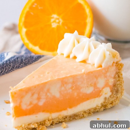 A slice of orange creamsicle cheesecake served on a white plate