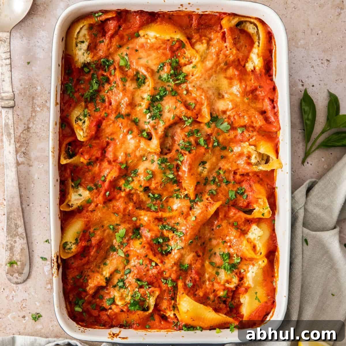 Large white and grey rectangular dish of Baked Tuna Pasta Shells, garnished with chopped parsley.
