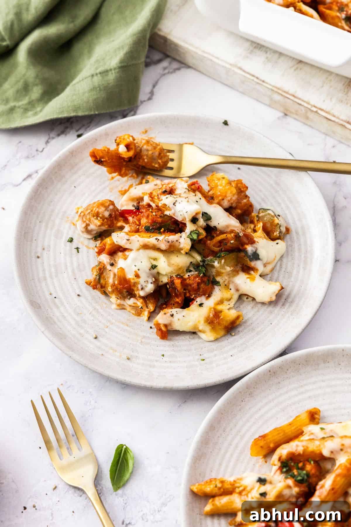 Serve of Mediterranean Sausage Pasta Bake on a round white plate, with a fork on the edge.