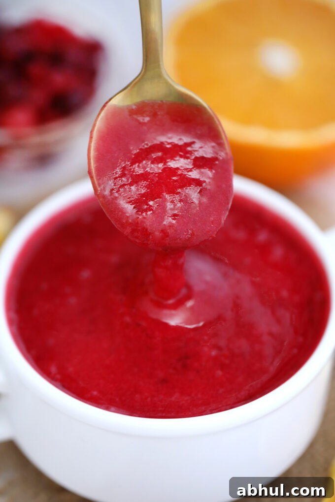 Homemade Cranberry Sauce dripping of a spoon into a bowl