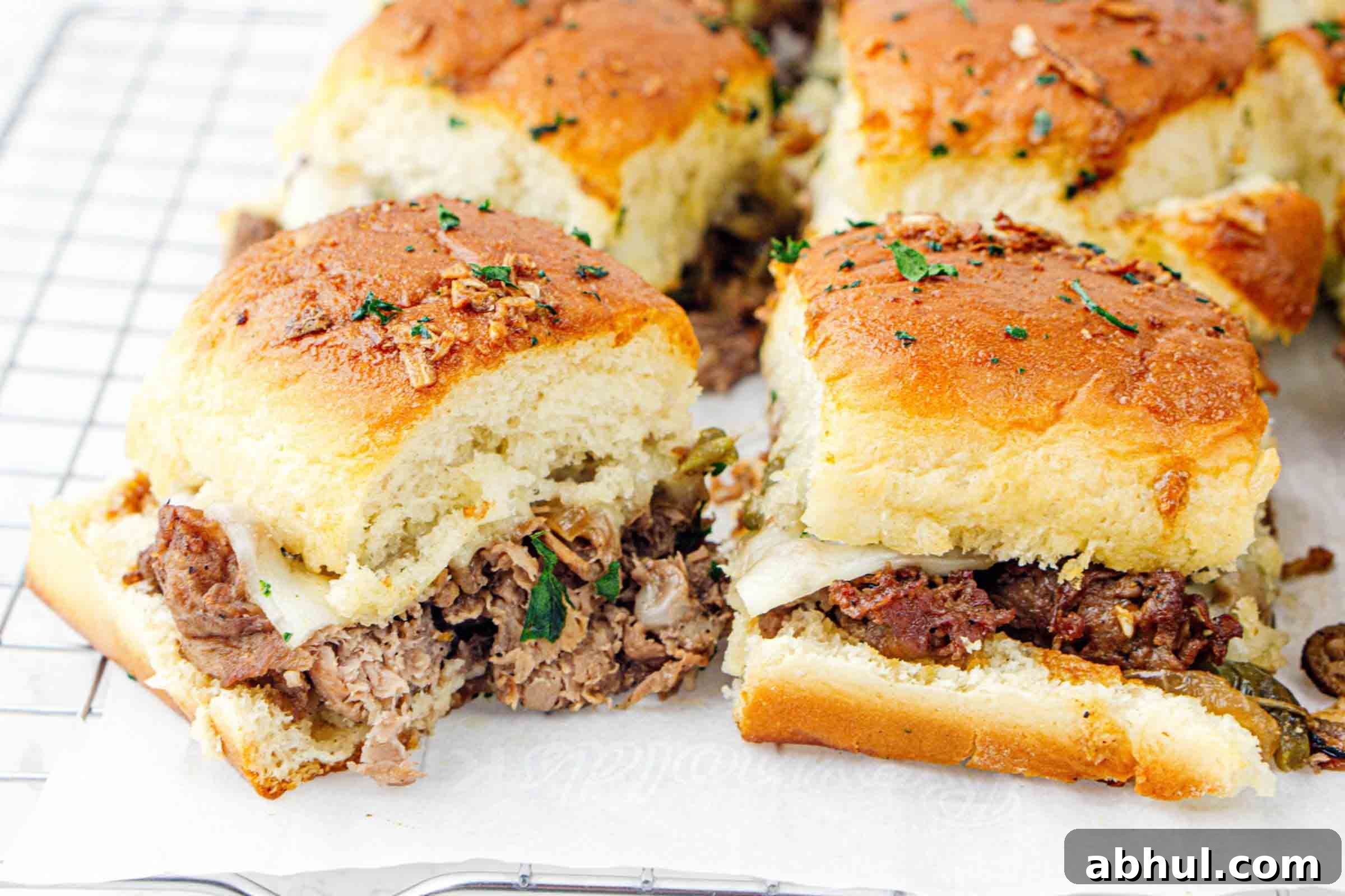 Philly cheesesteak sliders on parchment paper after baking.
