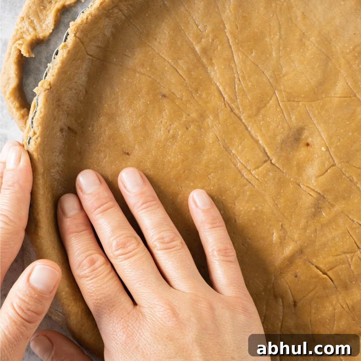 Pressing graham cracker dough into pie pan.