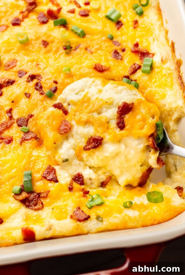 close-up of a serving spoon in a baking dish with loaded mashed potato casserole