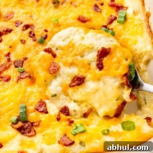 close-up of a serving spoon in a baking dish with loaded mashed potato casserole