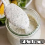 Homemade Herb Ranch Dressing Recipe for Fresh Flavor 7 A small jar of homemade ranch dressing with a spoon lifting some out.