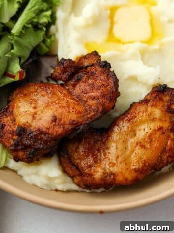 Two crisp chicken thighs on a bed of mashed potatoes.