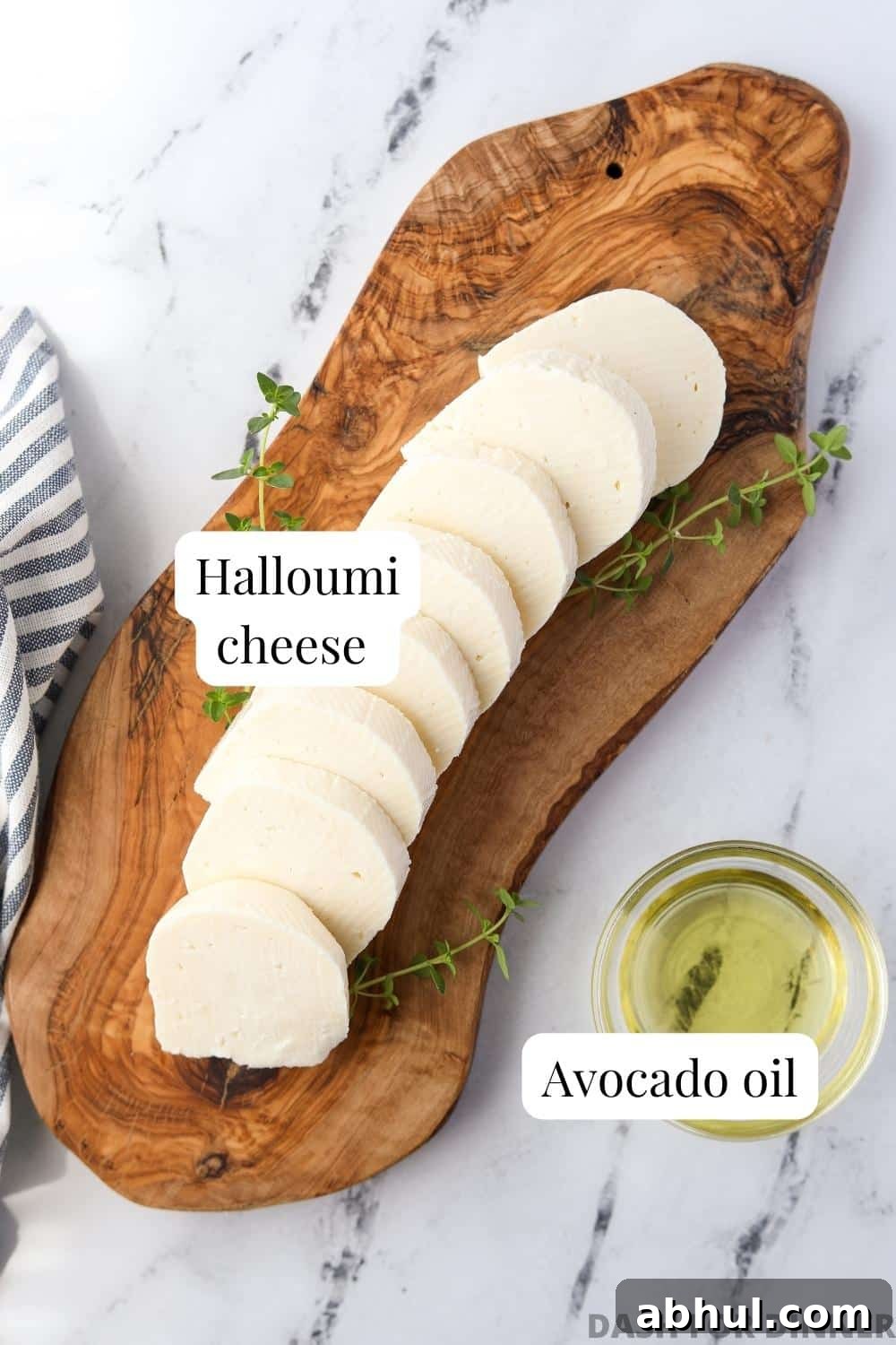 A wooden board with sliced halloumi and a small bowl of avocado oil.