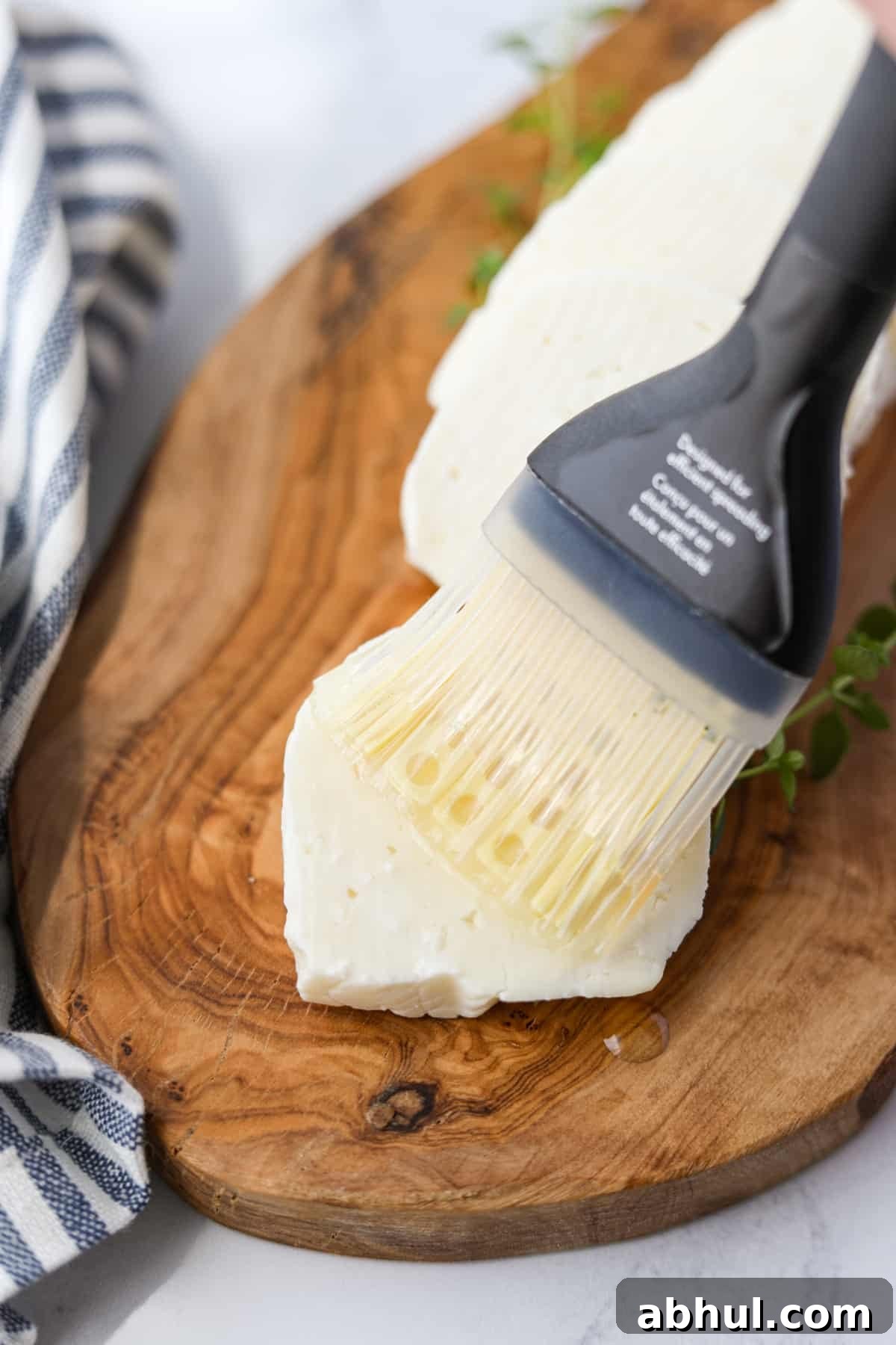 Brushing oil on a slice of halloumi cheese.