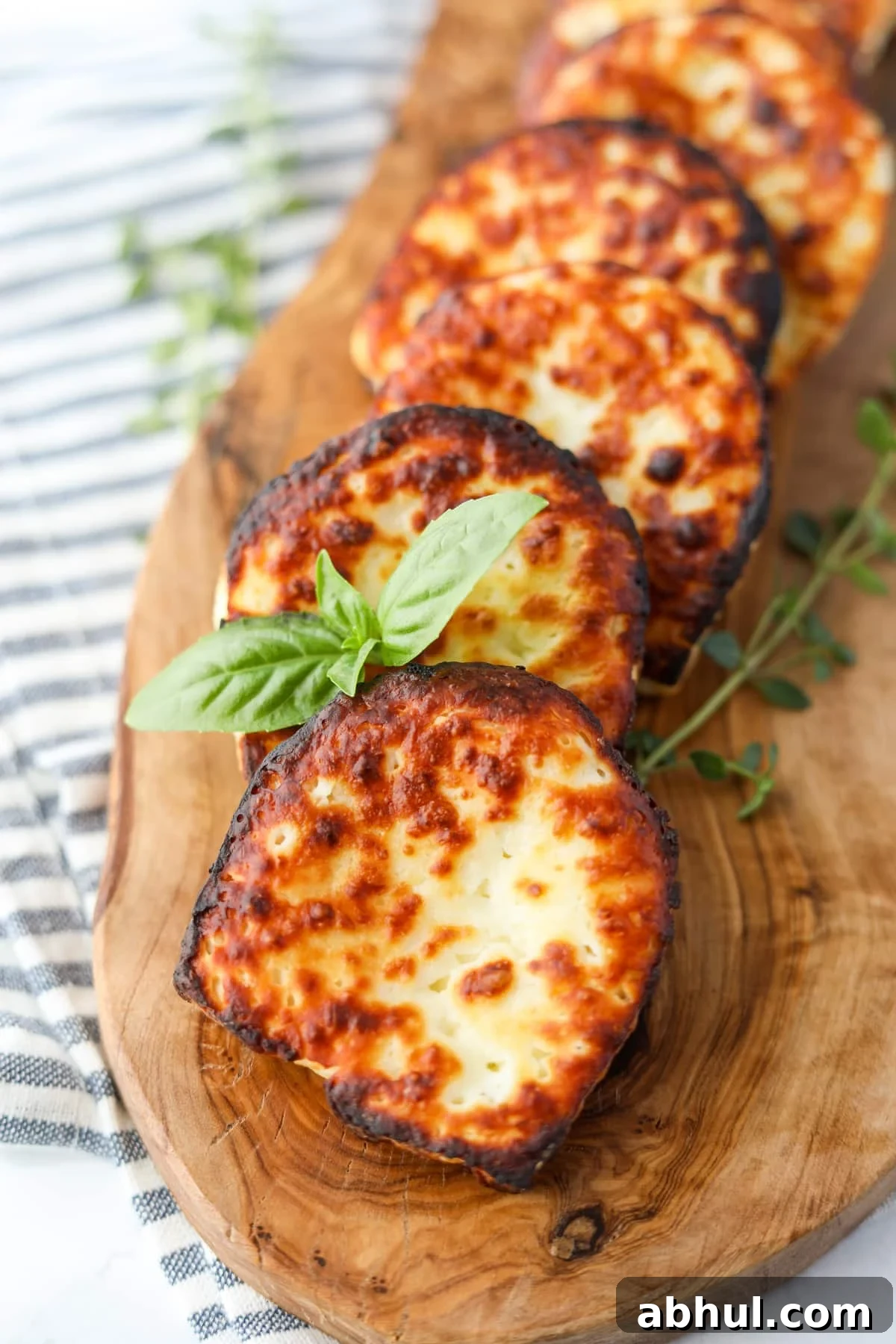 Fried cheese on a wooden board, garnished with basil.