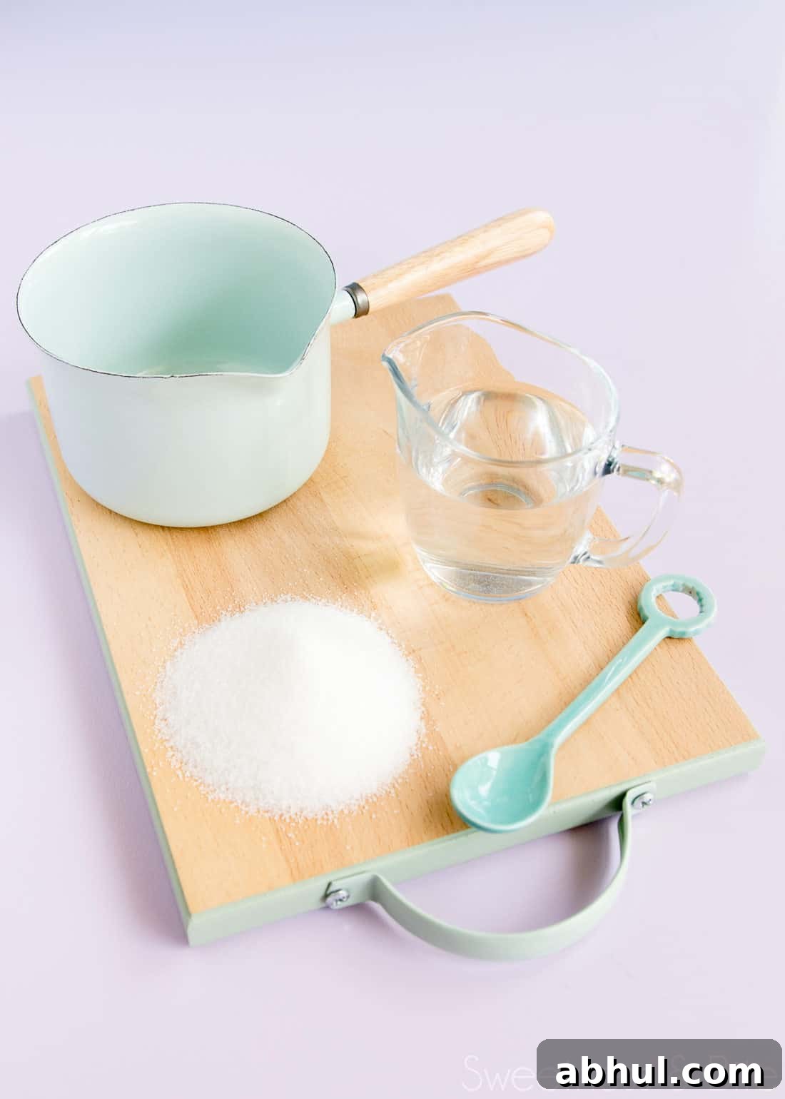 Sugar syrup ingredients and equipment - sugar, water, a small pan and a spoon.