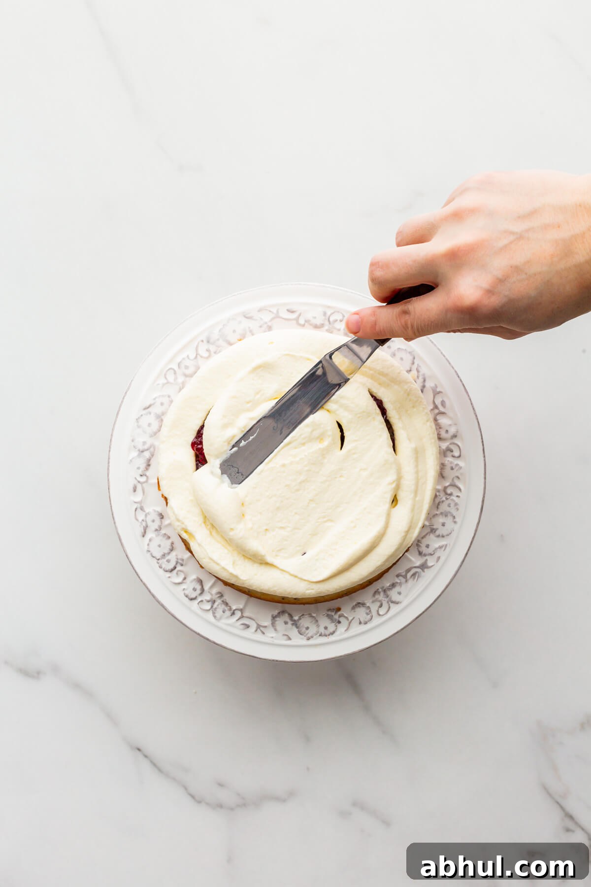 Smoothing frosting on a layer of cake with a mini offset spatula.