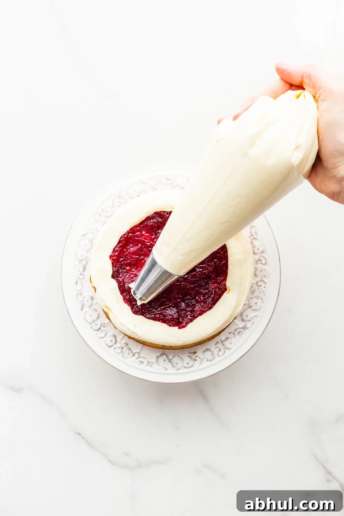 Piping frosting over cranberry compote to make a layer cake.