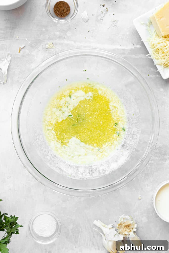 A glass bowl of melted butter with garlic and herbs.