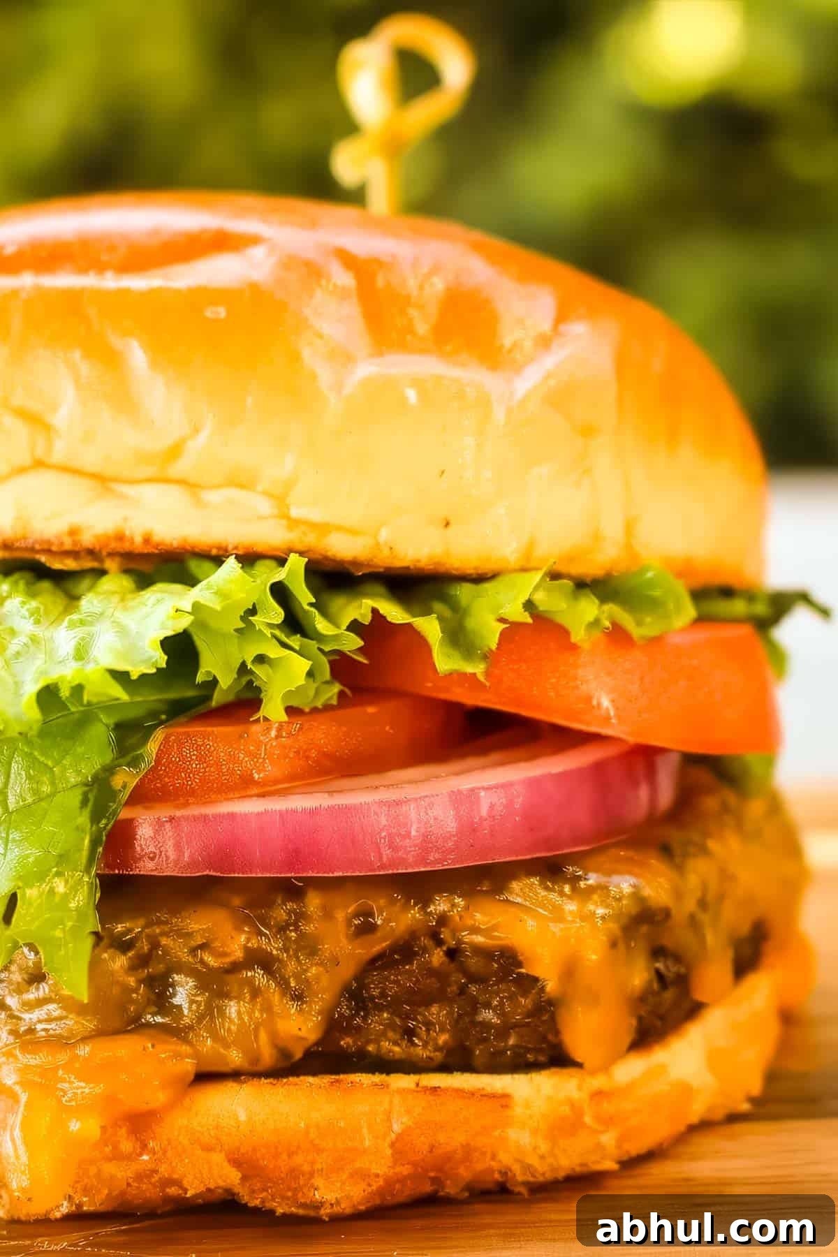 a smoked hamburger topped with cheese, lettuce, onion, and tomato