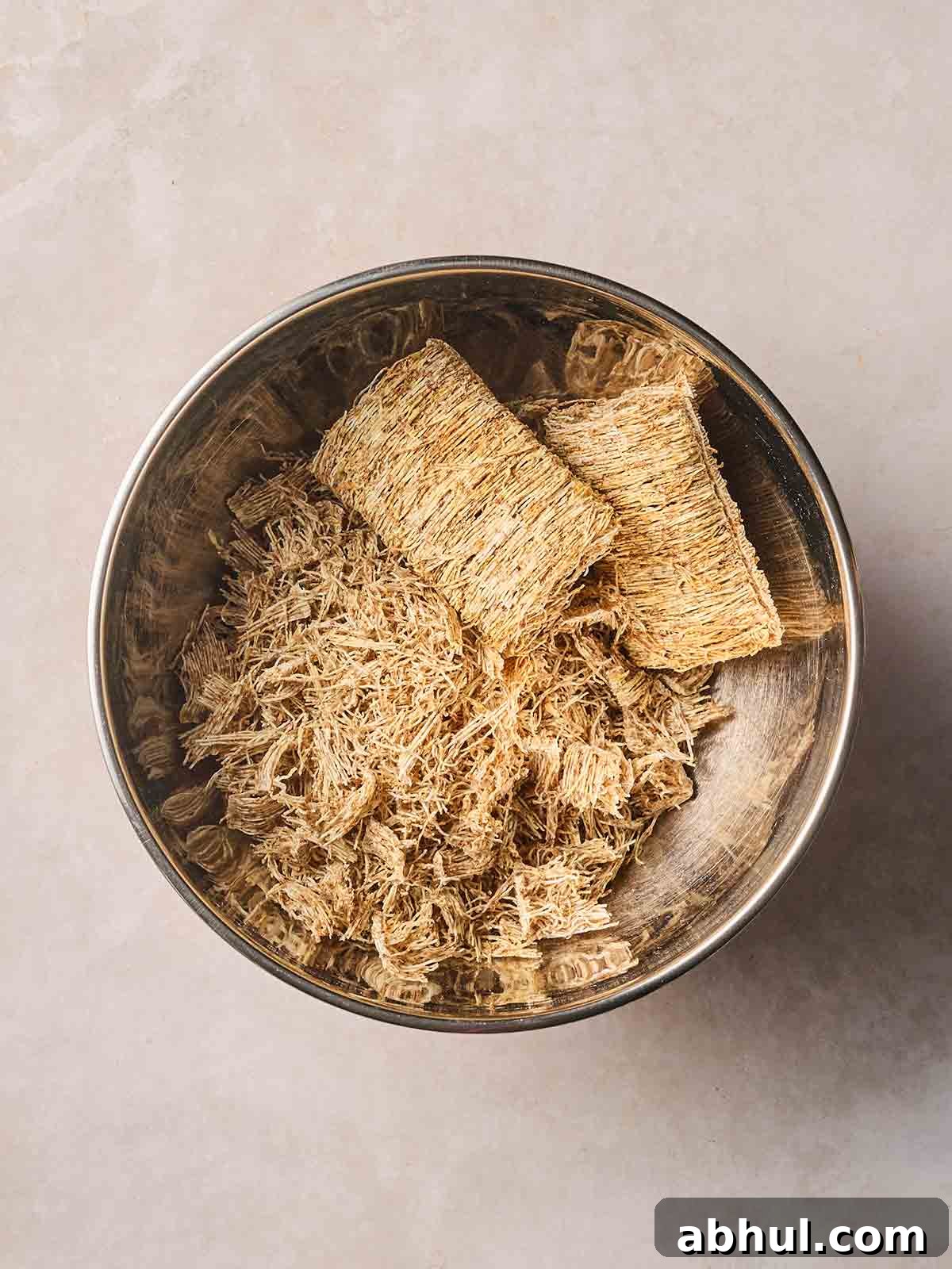 Shredded wheat slightly broken up in a bowl.