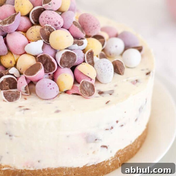 Cheesecake topped with pastel coloured candy eggs on a white plate.