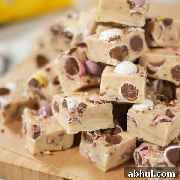 A pile of white chocolate mini egg fudge squares on a chopping board.