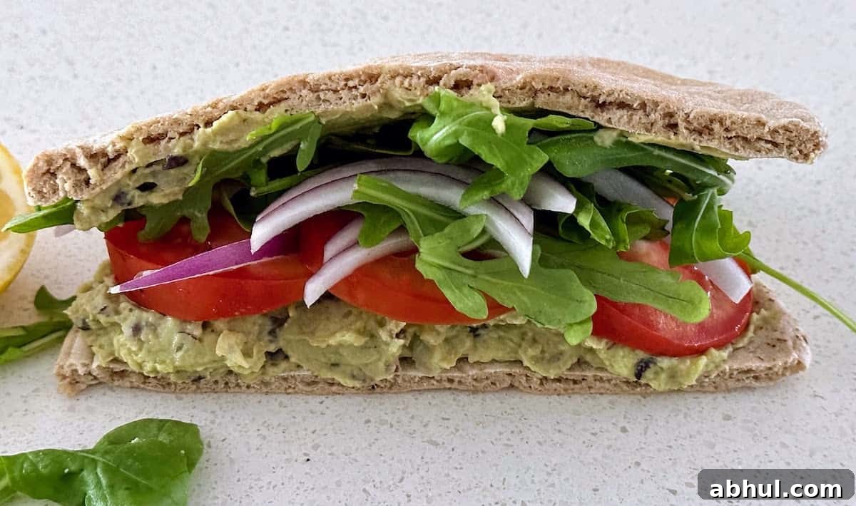 White bean avocado sandwich recipe on the a plate on the table. 