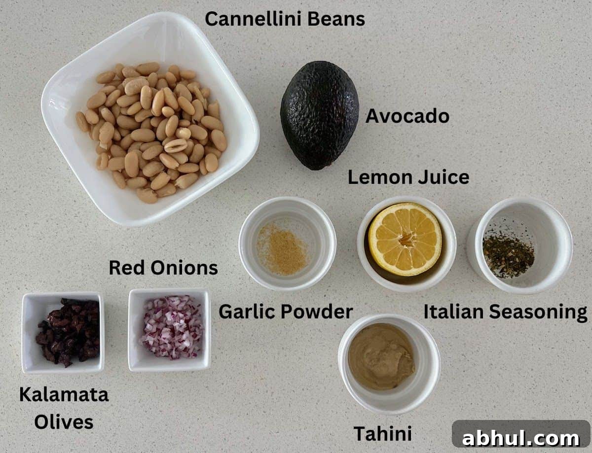 White beans dip ingredients: white beans, avocado, lemon, garlic powder, Italian seasoning, tahini, red onion, and kalamata olives. 