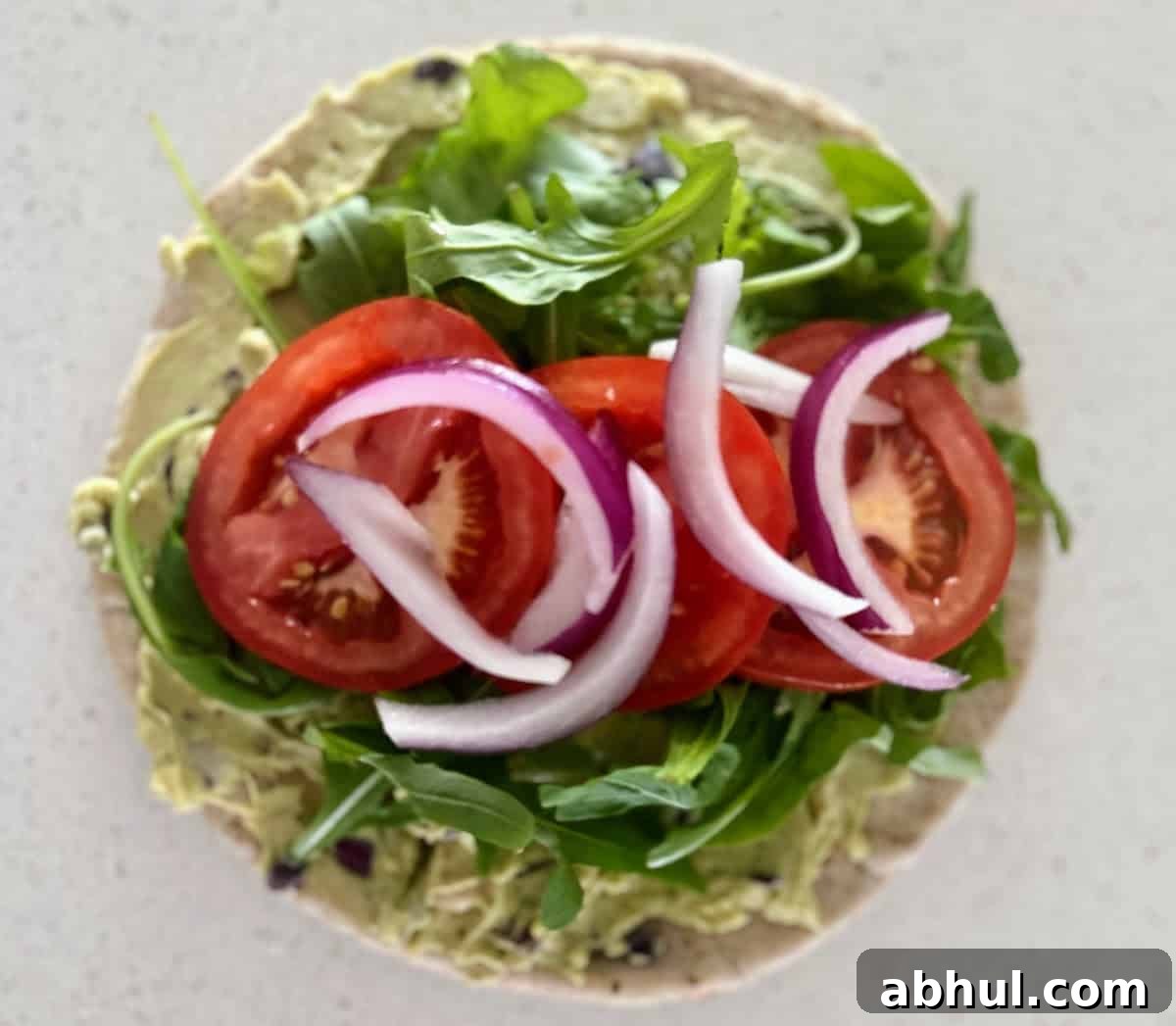 Arugula, tomato slices, and red onion on top of the bread and dip. 